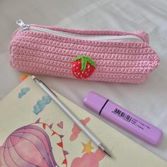 a strawberries pencil case next to a pen and marker