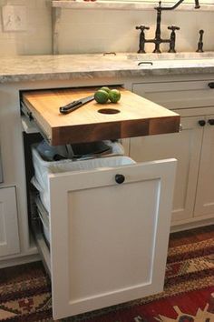 a kitchen with a cutting board and knife on the counter top next to an open drawer