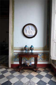 two vases sitting on top of a table in front of a wall mounted clock