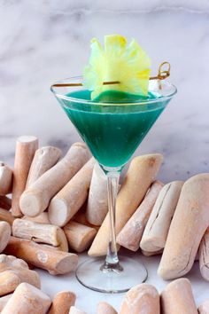 a green cocktail in a martini glass surrounded by wooden sticks