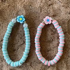 two bracelets with flowers on them sitting on the ground next to each other,