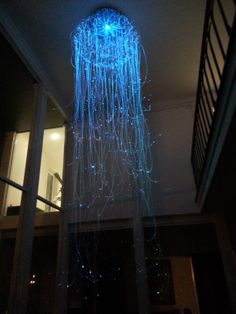 a blue light hanging from the ceiling in a dark room with stairs and railings