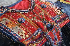 It is a beautiful Afghani dress with a beautiful greyish blue color and bright red threadwork. The contrast of red and blue colors make this dress an elegant piece of craft. It is embellished with beads, silver threadwork and coins. The fabric is of very good quality. It is light, trendy and sparkling. Red Embellished Dress For Navratri, Red Bohemian Ceremonial Dress, Red Mirror Work Dress For Festivals, Red Bohemian Dress For Ceremonial Occasions, Red Dress With Mirror Work For Festivals, Bohemian Dress For Festivals And Celebrations, Red Dresses With Motifs For Traditional Ceremonies, Bohemian Embroidered Celebration Dress, Bohemian Embroidered Dress For Celebration