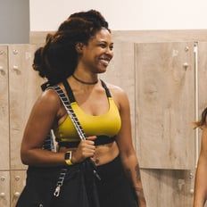 two women standing next to each other in front of lockers with one holding a bag