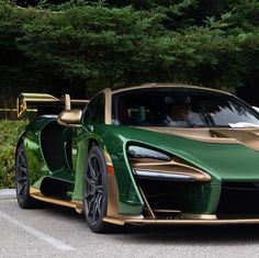 a green and gold colored sports car parked in a parking lot next to some trees