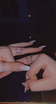 two hands with butterfly tattoos on their fingers