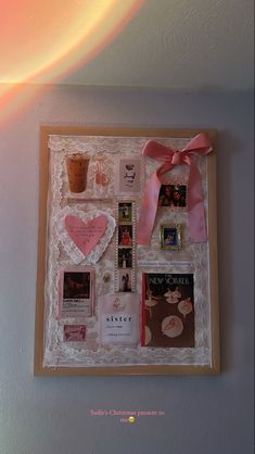 a wall hanging with pictures, cards and a pink bow on it's side