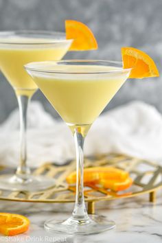 two martini glasses with orange wedges on the rim and one glass filled with white wine