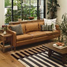 a living room filled with lots of furniture and plants in front of a large window