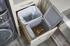 an open trash can next to a washer and dryer