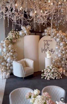 a room decorated with white balloons and chandeliers