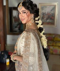 a woman in a white and gold bridal gown with her hair pulled back into a bun