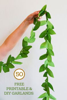 someone holding up some green leaves with the text 50 free printable and diy garlands