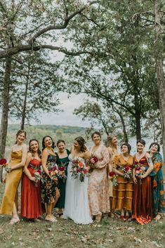 a group of women standing next to each other in front of trees with flowers on them