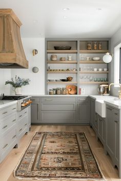 a kitchen with gray cabinets and white counter tops, an area rug on the floor