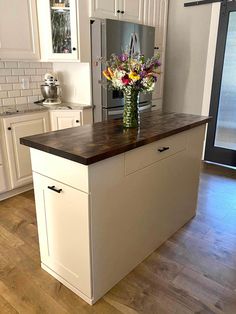 a kitchen island with flowers on it in front of a refrigerator