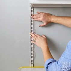 a woman measuring the height of a wall with a ruler on it's side