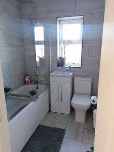 a bathroom with a toilet, sink and bathtub next to a window in it