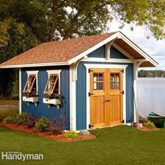 a blue and yellow shed sitting next to a body of water