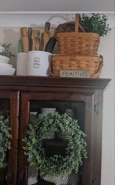 a wooden cabinet with plants and baskets on top