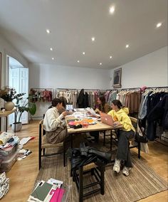 two people sitting at a table in a clothing store