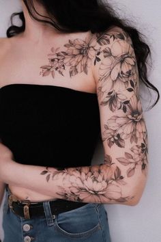 a woman's arm with flowers on it and her arms wrapped around the shoulder