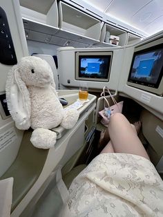 a stuffed animal sitting on top of an airplane bed next to two televisions and monitors