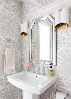 a white sink sitting under a bathroom mirror next to a wall mounted faucet