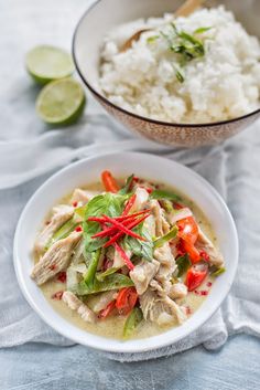 a white bowl filled with food next to a bowl of rice and lime wedges