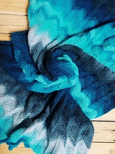 a blue and black scarf laying on top of a wooden floor