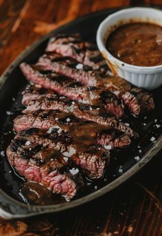 grilled steaks with sauce in a pan on a wooden table