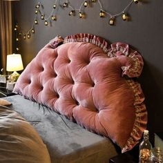 a bed with a pink tufted headboard and pillows on it's sides