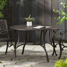 an outdoor table with two chairs and a potted plant