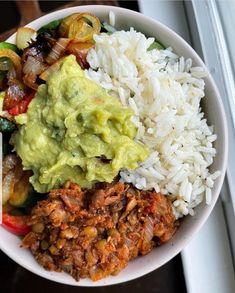 a bowl filled with rice, meat and veggies on top of a window sill