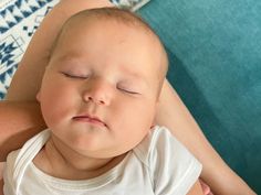 a woman is holding a sleeping baby on her lap