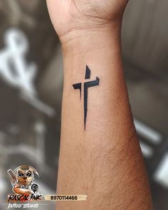 a tattoo on the wrist of a person with a cross tattooed on it's arm