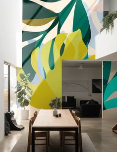 a dining room table and chairs in front of a colorful wall