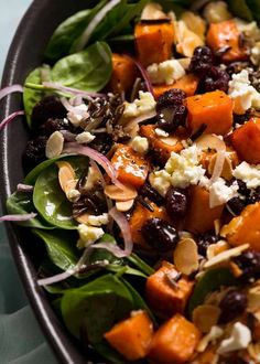 a salad with spinach, carrots, feta cheese and cranberries