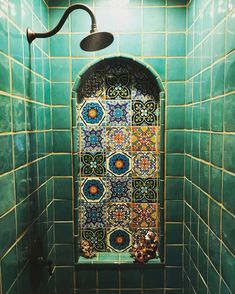 a green tiled bathroom with a shower head