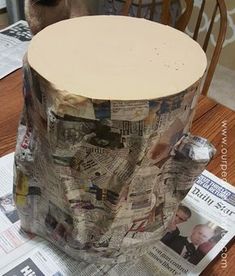 a paper mache sitting on top of a wooden table next to a newspaper roll