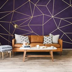 a brown leather couch sitting in front of a purple wall with gold lines on it