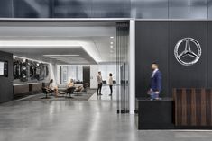 people are standing in an office lobby with the mercedes logo on the wall behind them