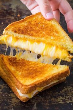 a grilled cheese sandwich being held by someone