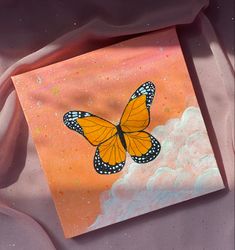 an orange and black butterfly is on a pink background with some white clouds in the foreground