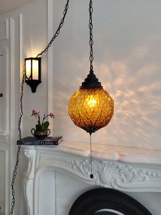 a lamp hanging from a chain next to a fireplace