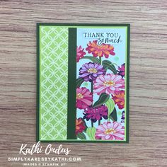 a handmade thank card with pink flowers on green and white paper, sitting on top of a wooden table