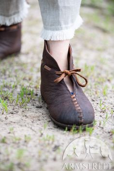 a person wearing brown shoes standing in the grass