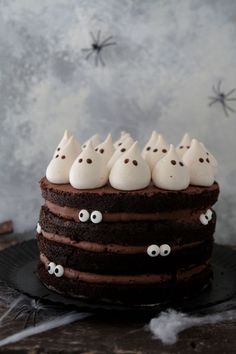 a chocolate cake topped with white frosting and sprinkles decorated with eyes