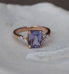 a tan and blue ring with three diamonds on the side, sitting on top of a rock