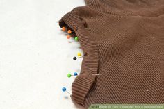 a brown sweater with buttons on it laying on top of a white table next to a pair of scissors